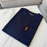 Studio By Charles navy pocket tee neatly folded on white marble table next to beige sofa