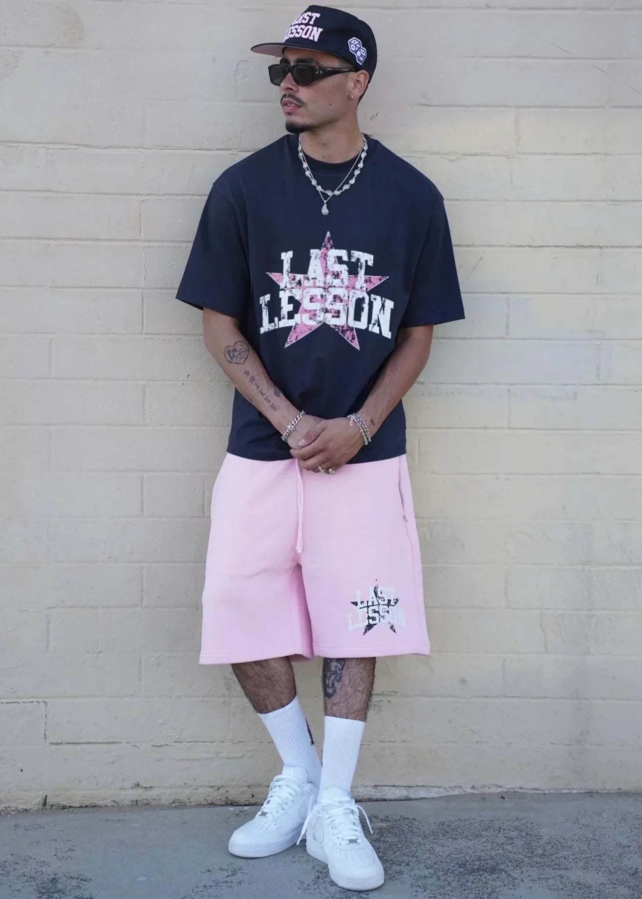 Last Lesson All-Star Shorts in pink worn by model with matching T-shirt and cap.