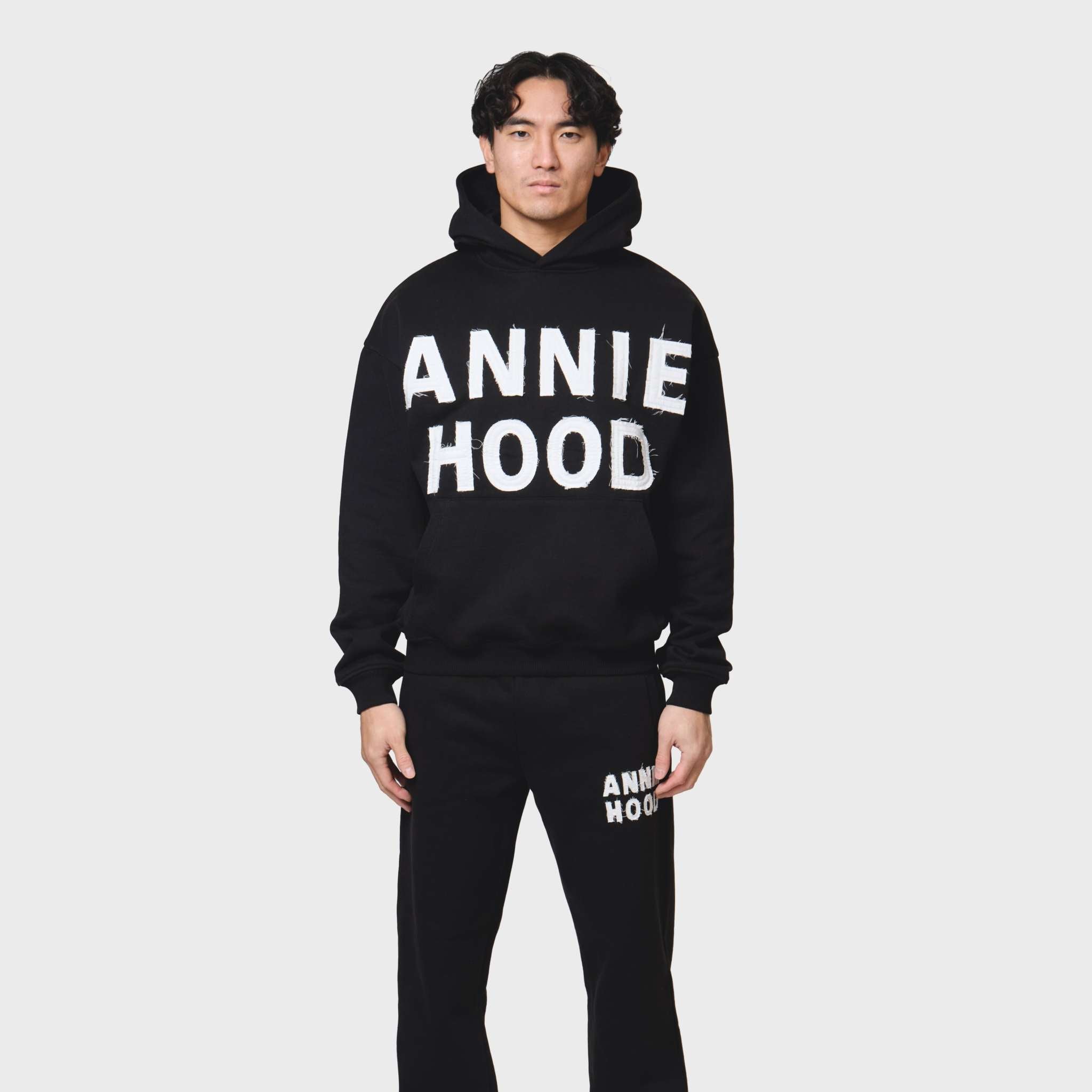 Annie Hood Applique Hoody in black with relaxed fit, 500gsm brushback cotton, modeled by 6'0" figure wearing size M
