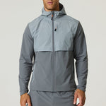 Man wearing a slate and light grey Reprimo Summit Windbreaker with hood and full zipper, designed for lightweight comfort and active movement