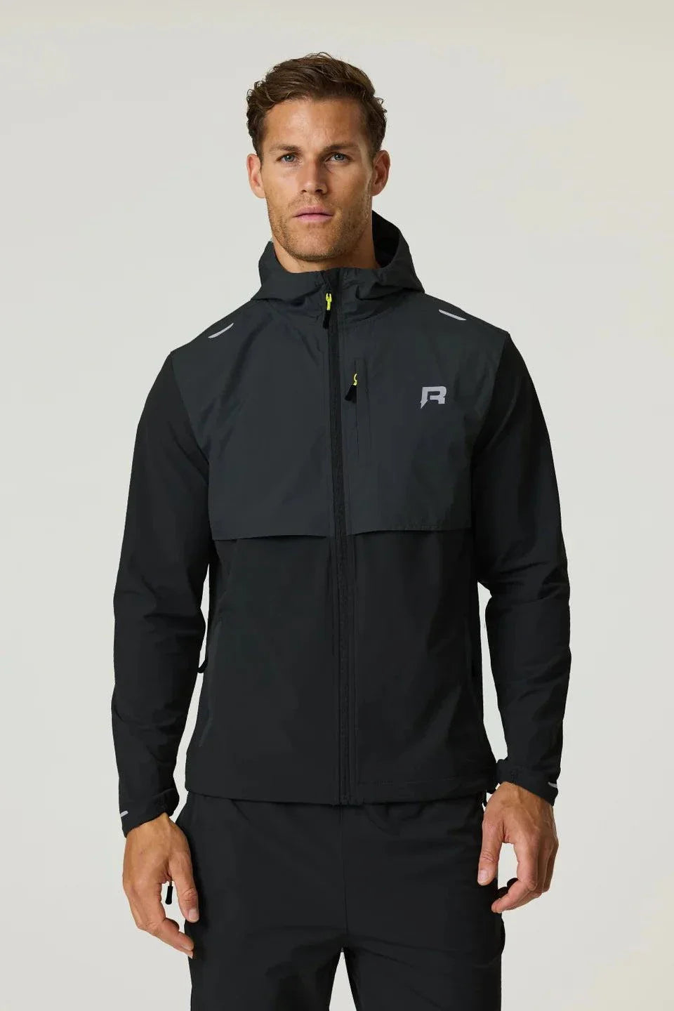 Reprimo Summit black windbreaker jacket with hood and yellow zipper detail worn by male model