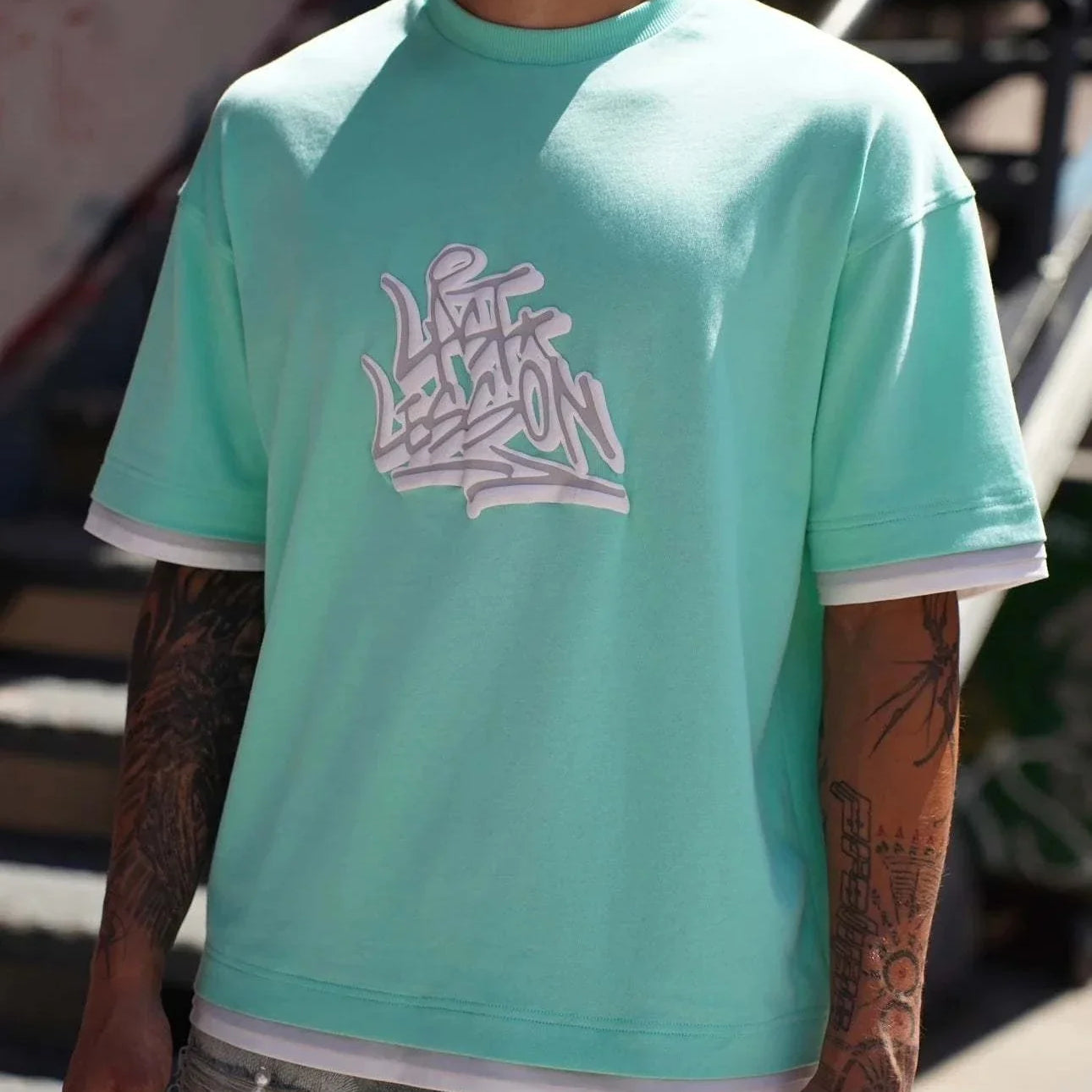 Last Lesson Graffiti 3 Layer T-Shirt in mint green with graffiti design.