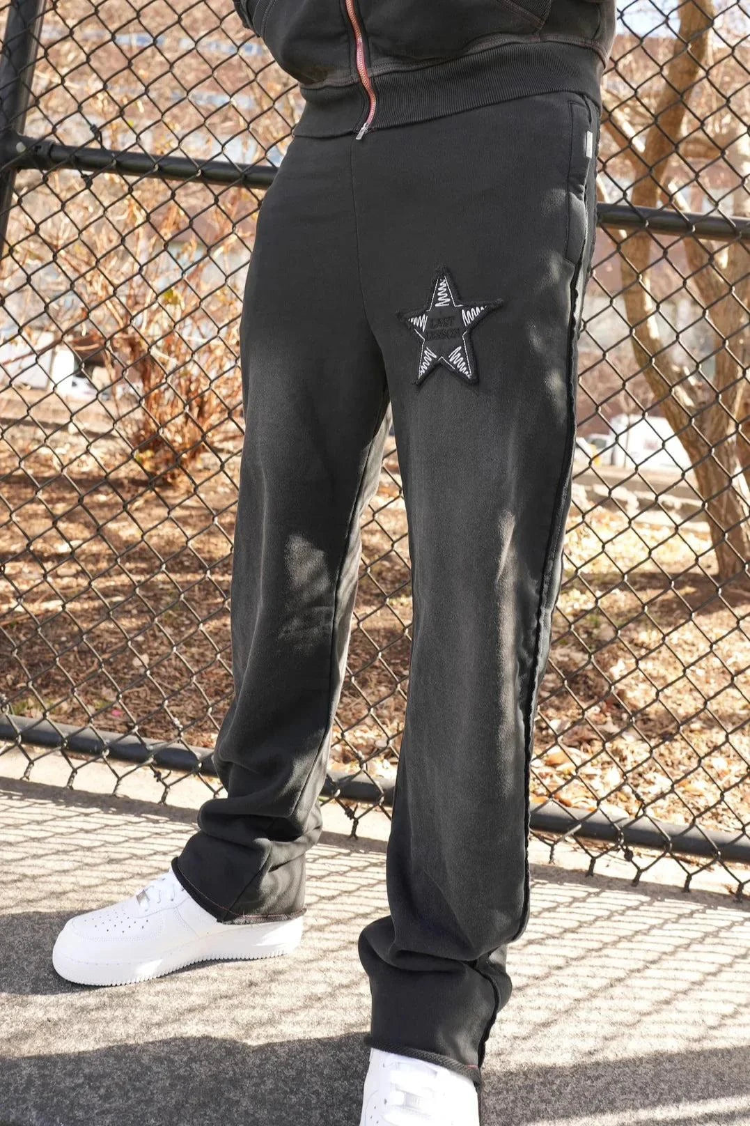 Black joggers with star appliqué and embroidered artwork, featuring a casual fit.