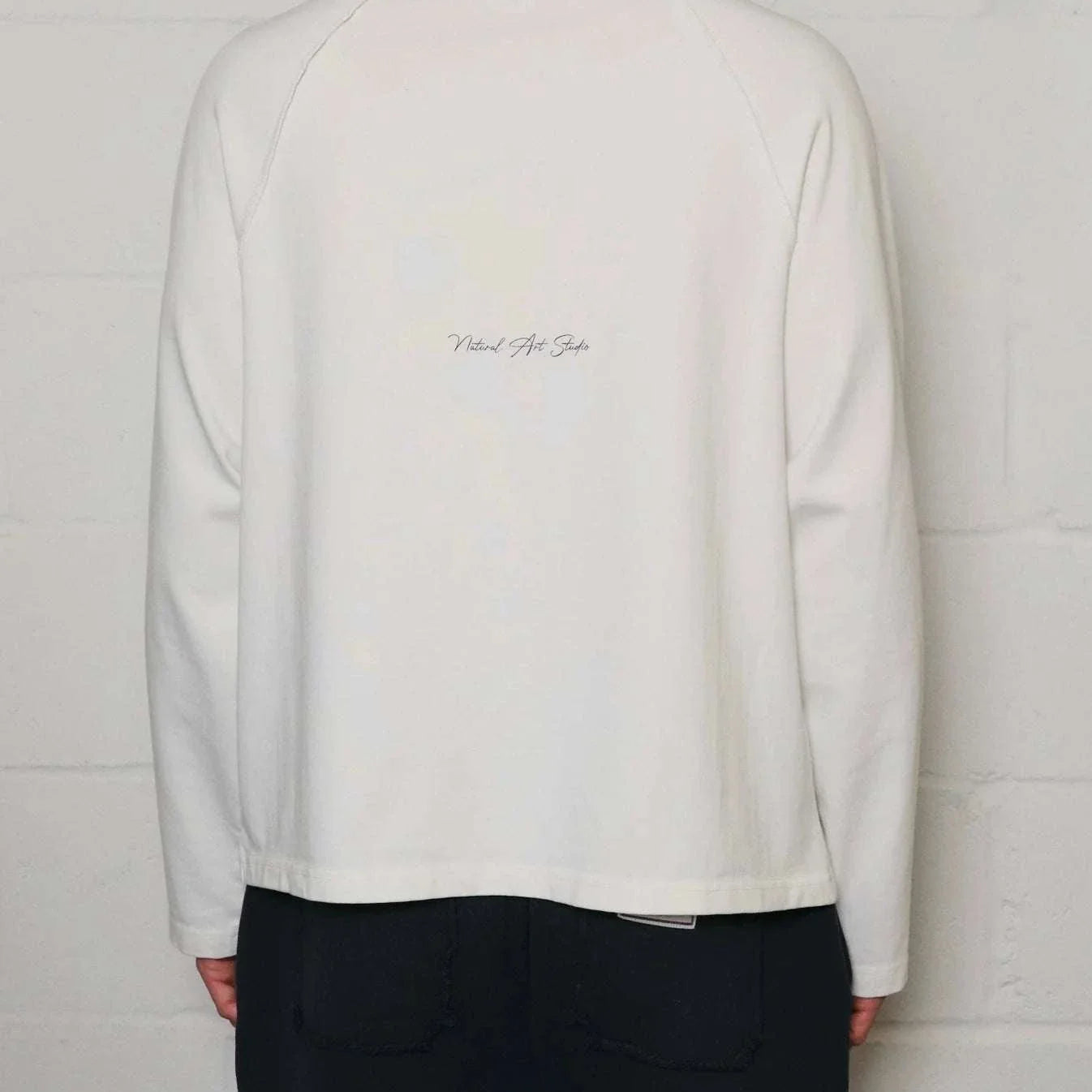Back view of Natural Art Studio white appliqué long sleeve cotton shirt with screen print logo and boxy fit