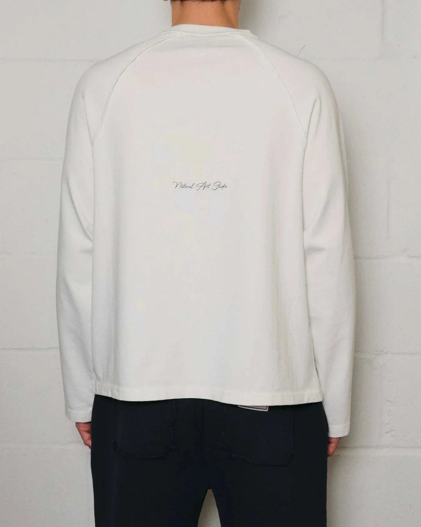 Back view of Natural Art Studio white appliqué long sleeve cotton shirt with screen print logo and boxy fit
