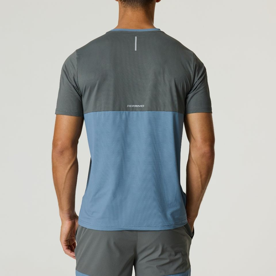 Rear view of a man wearing the Reprimo Flight T-Shirt in Air Force Blue and Gunmetal with matching shorts, featuring lightweight fabric and reflective strips for visibility.