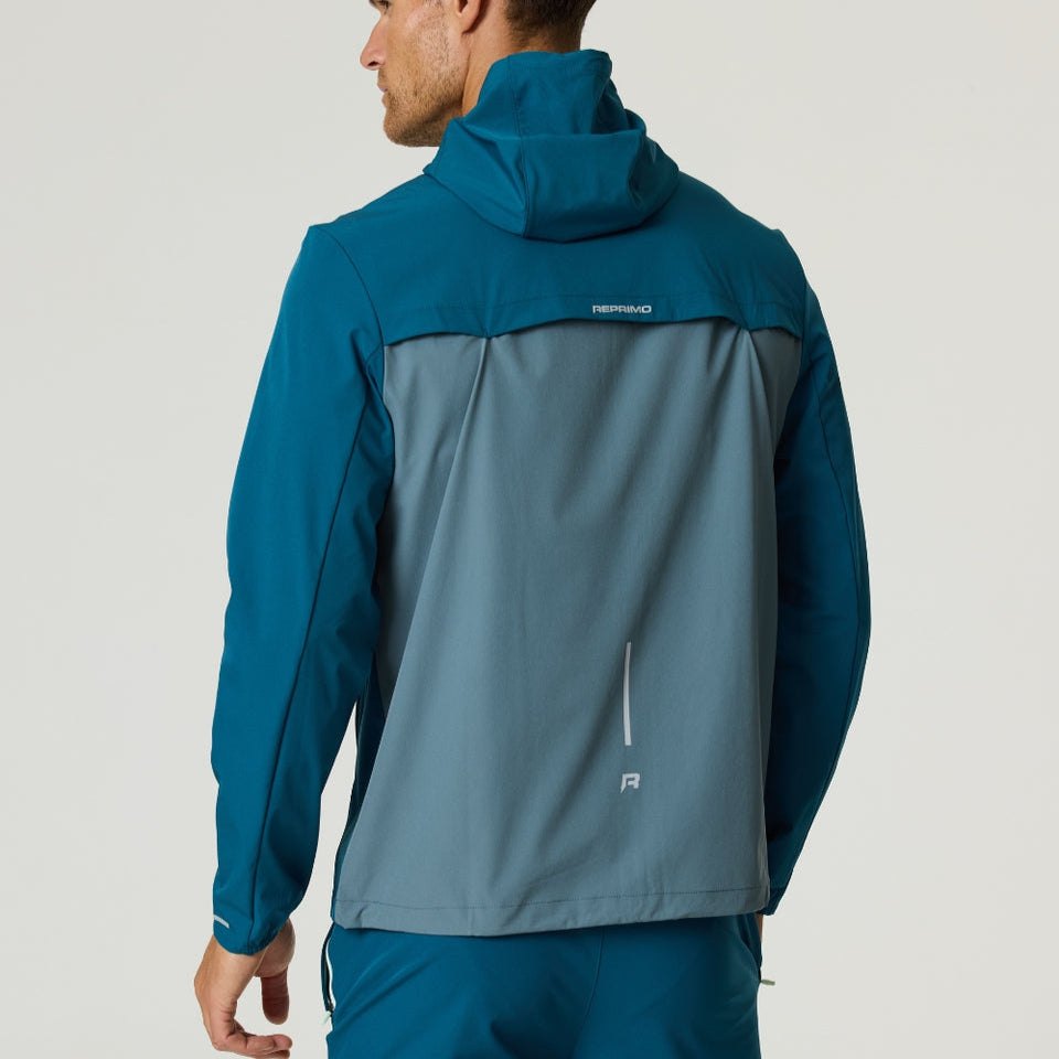 Man wearing Reprimo Flight Windbreaker in tidal teal and blue steel, lightweight weather-resistant jacket with back vent and zip pockets