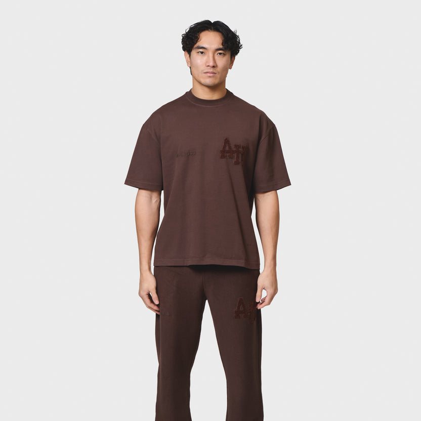 Male model wearing ANNIE HOOD COLLEGE T-SHIRT in washed brown, relaxed fit cotton tee