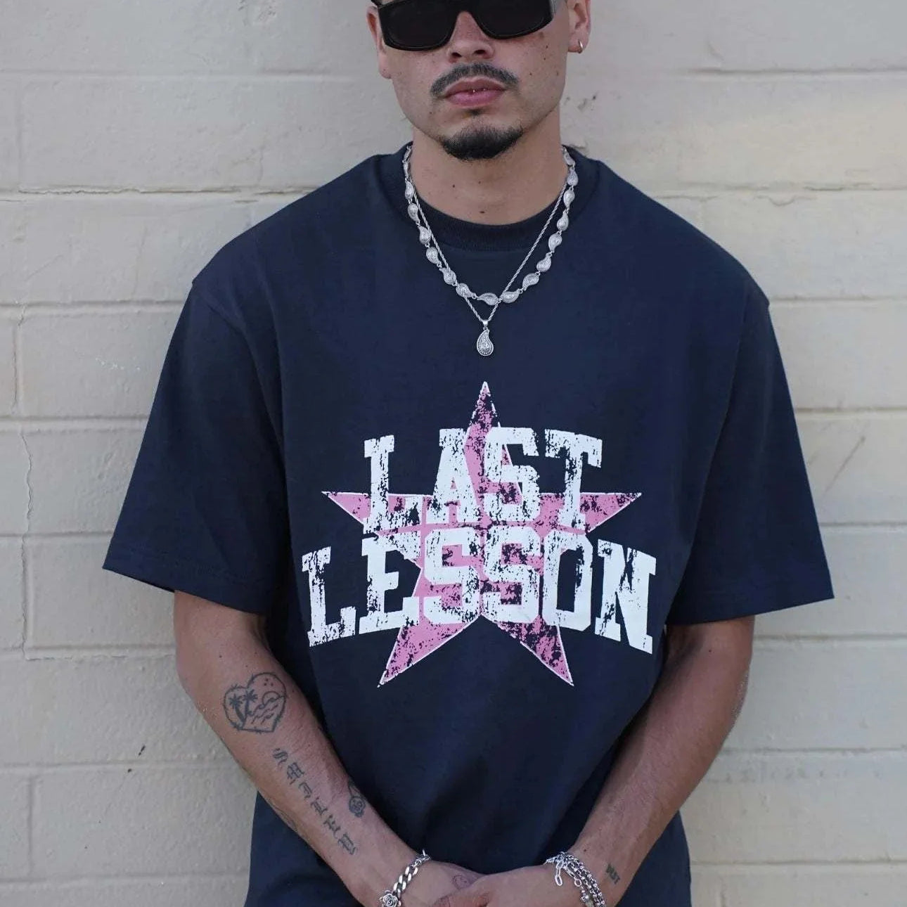 Man wearing Last Lesson All-Star Black T-Shirt with a star design, paired with a matching cap and sunglasses.