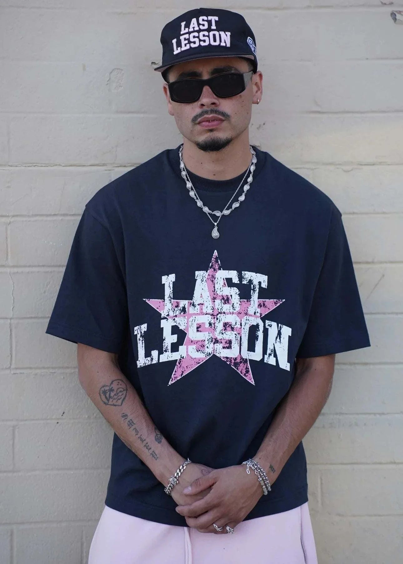 Man wearing Last Lesson All-Star Black T-Shirt with a star design, paired with a matching cap and sunglasses.