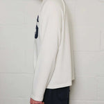 Side view of a man wearing Natural Art Studio white long sleeve appliqué cotton shirt with boxy fit and dropped shoulders
