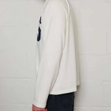 Side view of a man wearing Natural Art Studio white long sleeve appliqué cotton shirt with boxy fit and dropped shoulders