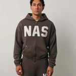 Man wearing Natural Art Studio NAS appliqué hoodie in dark color with white NAS logo and matching pants