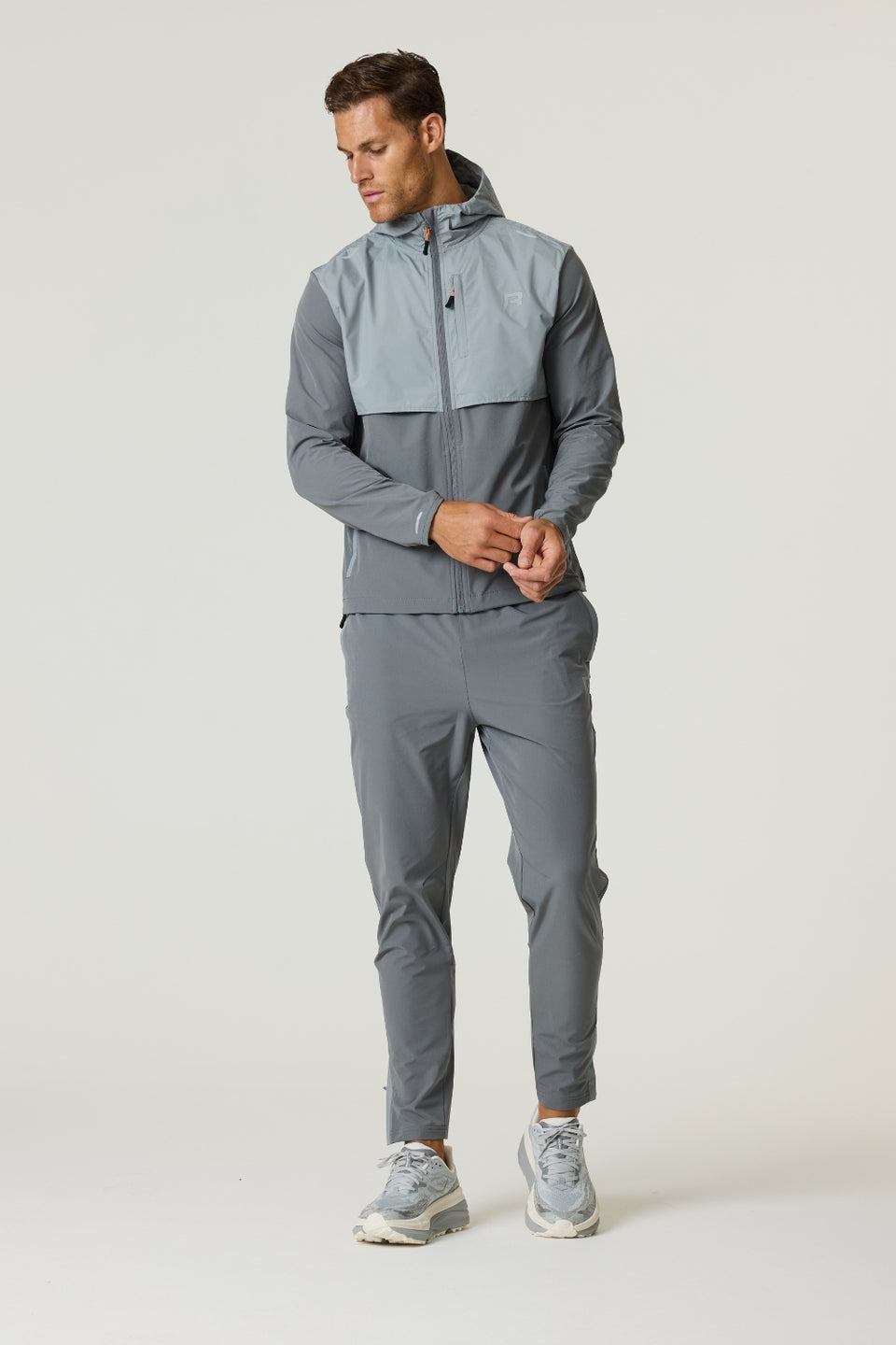 Man wearing Reprimo Summit Windbreaker in slate and light grey with matching pants and sneakers