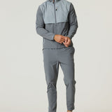 Man wearing Reprimo Summit Windbreaker in slate and light grey with matching pants and sneakers