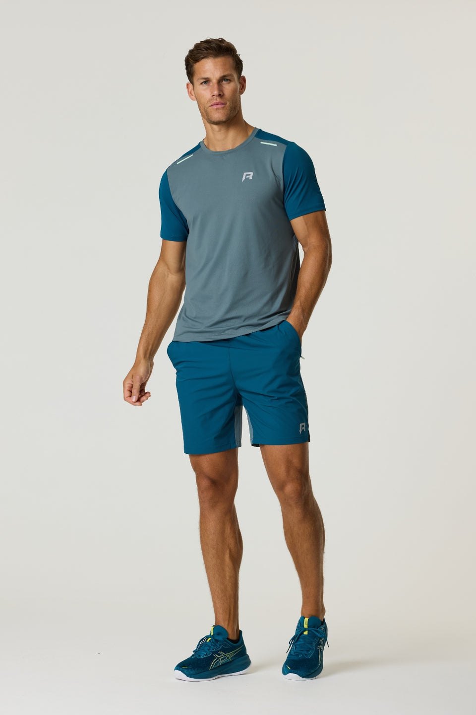 Athletic man wearing Reprimo Flight T-Shirt in tidal teal and blue steel with matching shorts and running shoes