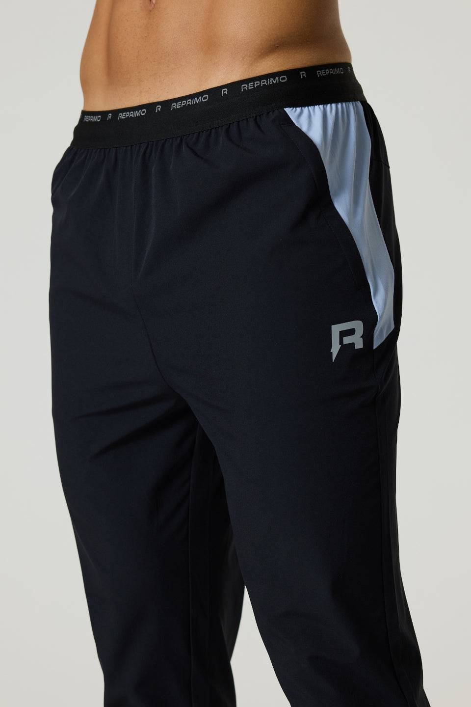 Black Reprimo Flight Pants with dusky sky side panels, elastic waistband, functional zippered pockets, and reflective strips for visibility.