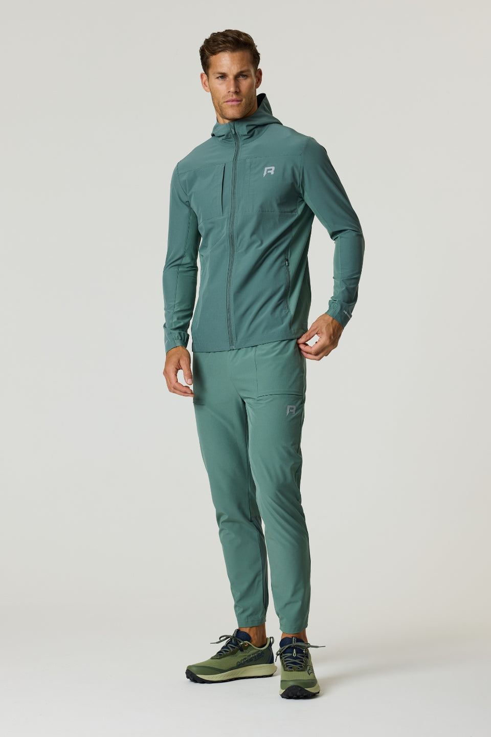 Man wearing Reprimo Glide Pants in botanical pine with tapered fit, textured breathable fabric, and seam-embedded pockets.