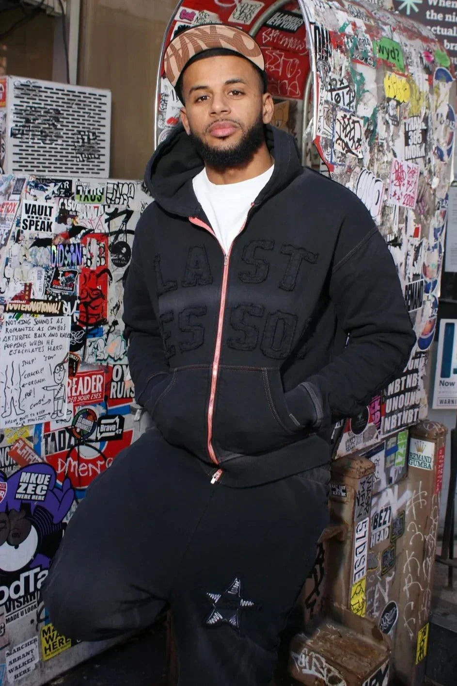 Last Lesson Appliqué Black Hoodie worn by model in urban setting.