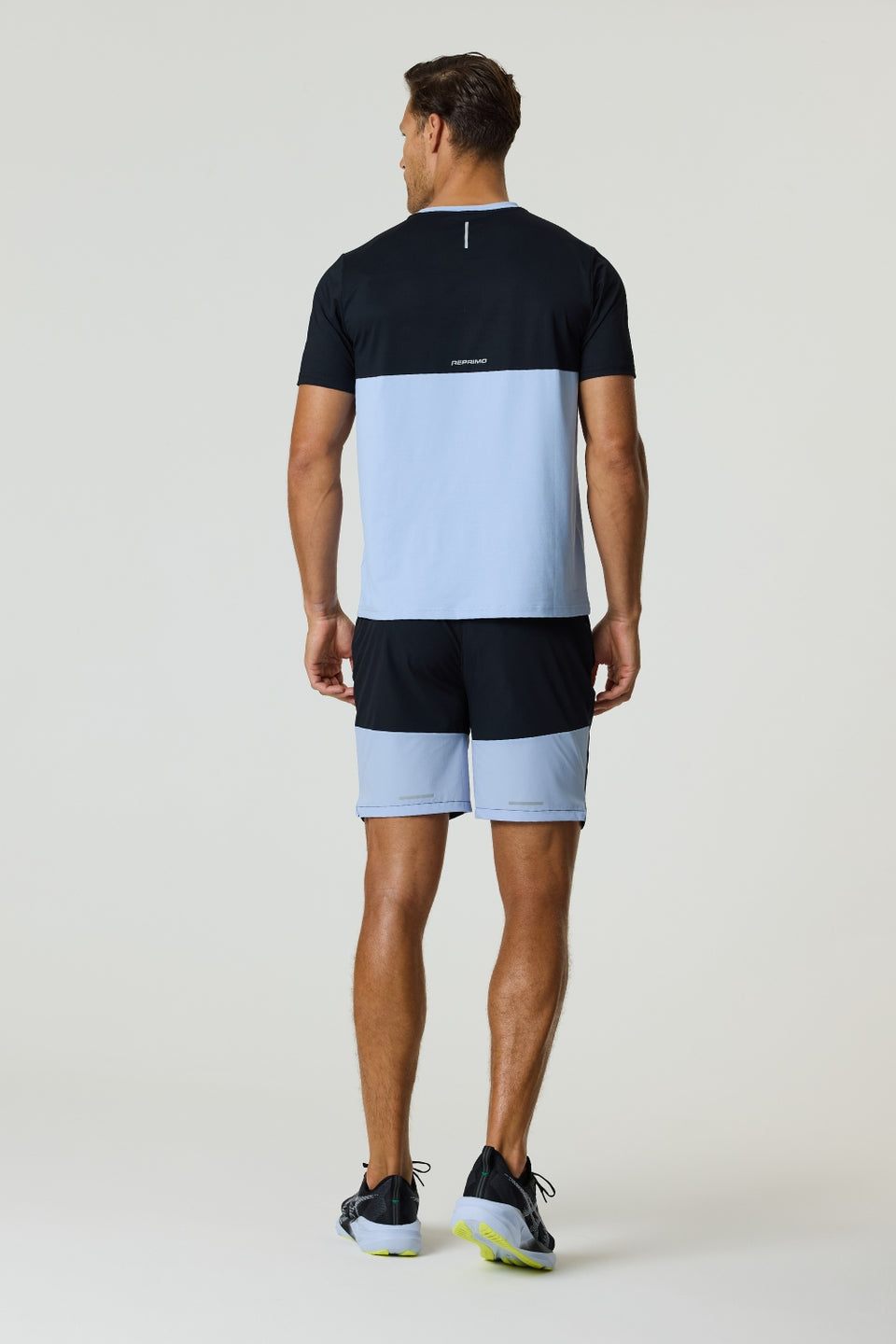 Rear view of a man wearing a black and dusky sky Reprimo Flight T-Shirt with athletic fit and reflective strip, paired with matching shorts