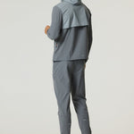 Man wearing slate and light grey Reprimo Summit Windbreaker with hood and matching pants, showcasing lightweight and reflective outdoor jacket.