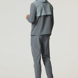 Man wearing slate and light grey Reprimo Summit Windbreaker with hood and matching pants, showcasing lightweight and reflective outdoor jacket.