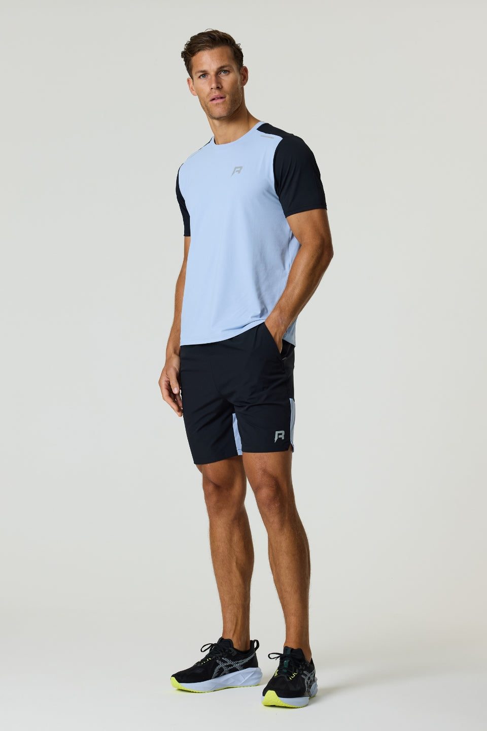 Athletic man wearing black Reprimo Flight Shorts with side zip pockets and light blue and black performance t-shirt