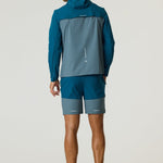 Man wearing Reprimo Flight Windbreaker in tidal teal and blue steel from the back, showcasing lightweight weather-resistant jacket with hood and zippered pockets.
