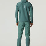 Man wearing botanical pine Reprimo Glide Jacket and matching pants standing back facing white background