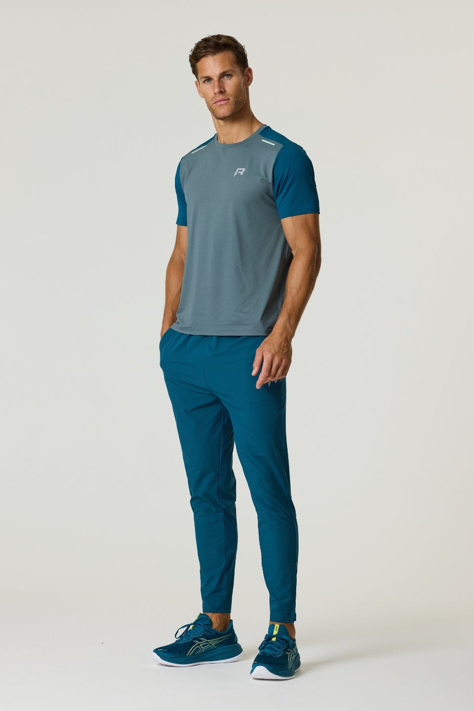 Athlete wearing Reprimo Flight Pants in tidal teal with functional pockets and reflective strips for performance and comfort