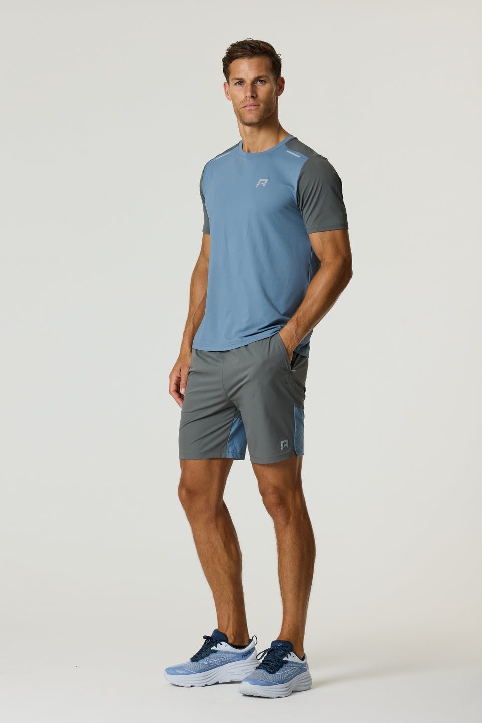 Man wearing Reprimo Flight Shorts in Air Force Blue and Gunmetal with breathable fabric and secure side pockets.