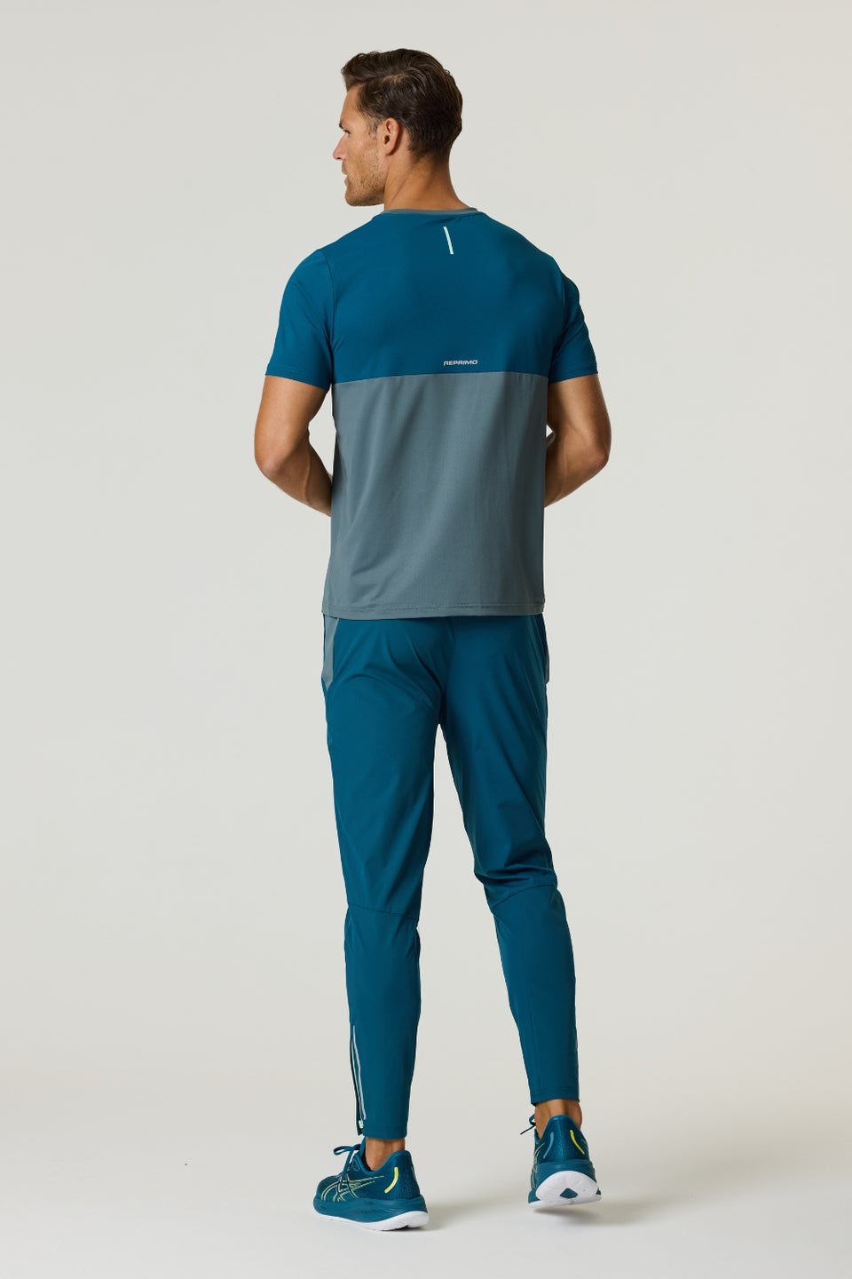 Rear view of man wearing Reprimo Flight T-Shirt in tidal teal and blue steel with reflective strips and athletic fit