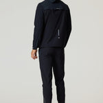 Rear view of man wearing black Reprimo Flight Windbreaker with hood and zip pockets, paired with black athletic pants and shoes.