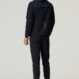 Rear view of man wearing black Reprimo Flight Windbreaker with hood and zip pockets, paired with black athletic pants and shoes.