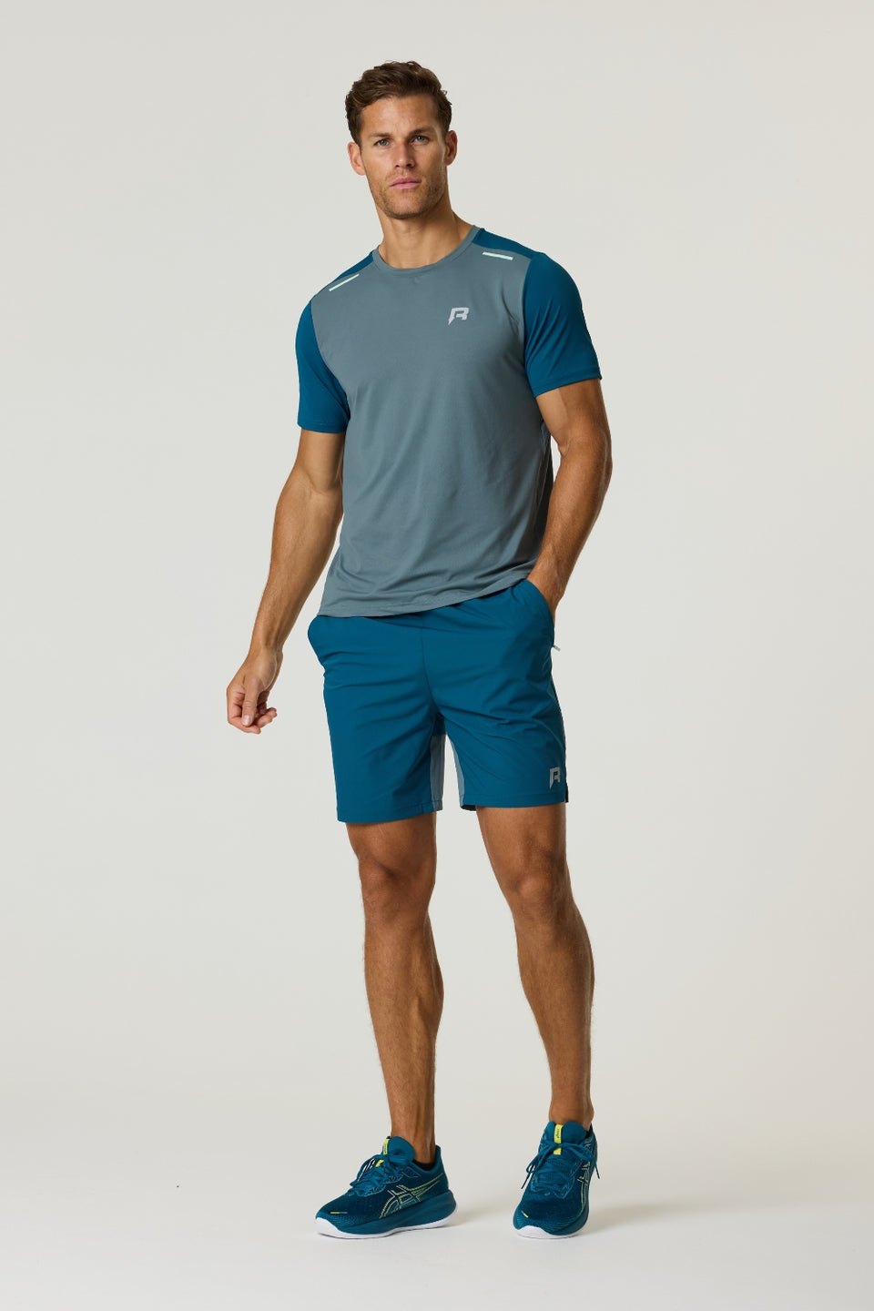 Athletic man wearing Reprimo Flight Shorts in tidal teal and blue steel with matching t-shirt and sneakers.