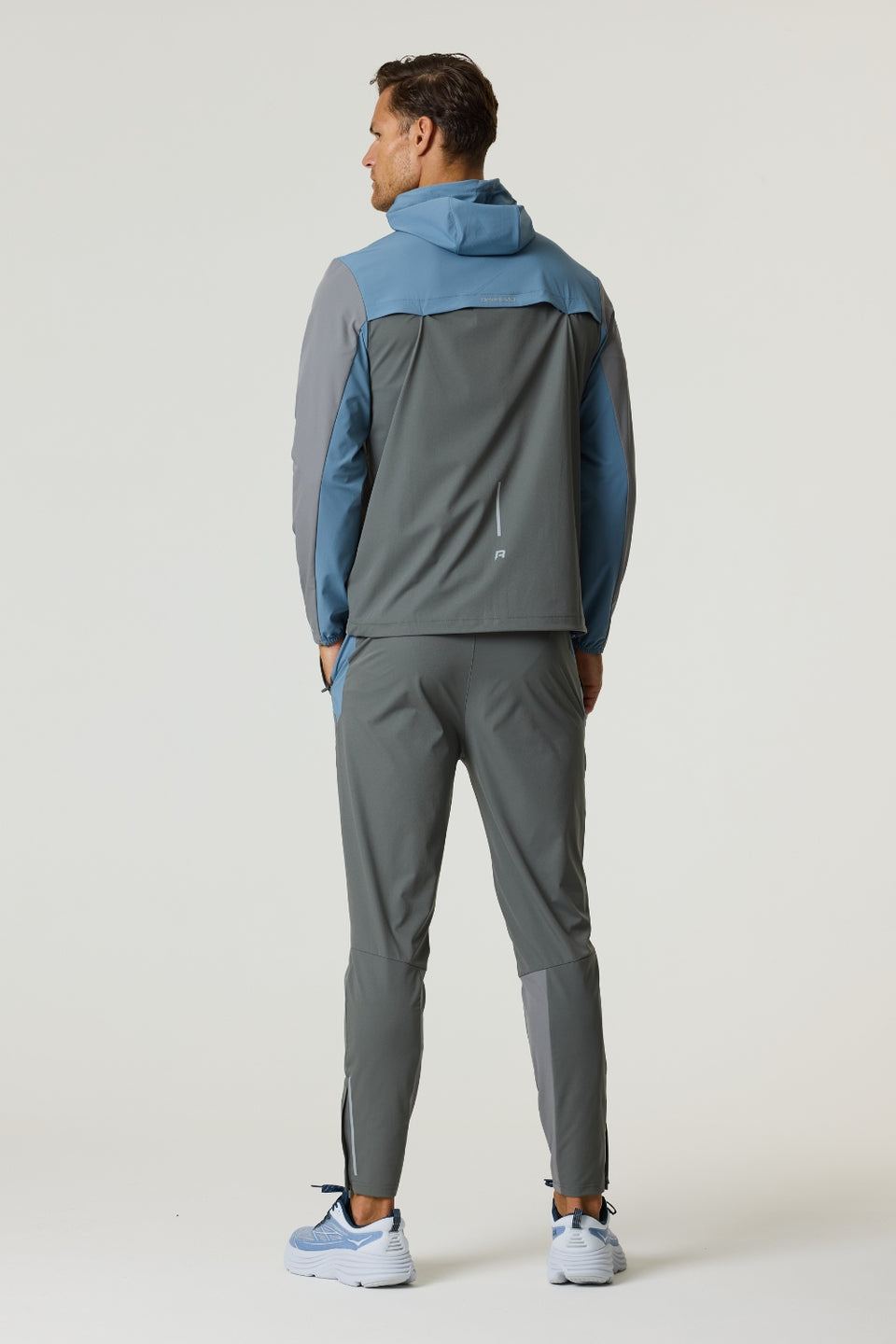 Man wearing Reprimo Flight Windbreaker in Air Force Blue and Gunmetal with hood and zip pockets, shown from back