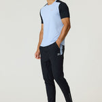 Athlete wearing black Reprimo Flight Pants with side pockets and reflective strips, paired with a light blue and black short-sleeve shirt.