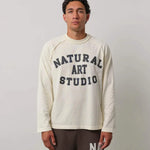 Man wearing Natural Art Studio Raglan long sleeve shirt with front logo print and raglan seams in cream color