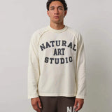 Man wearing Natural Art Studio Raglan long sleeve shirt with front logo print and raglan seams in cream color