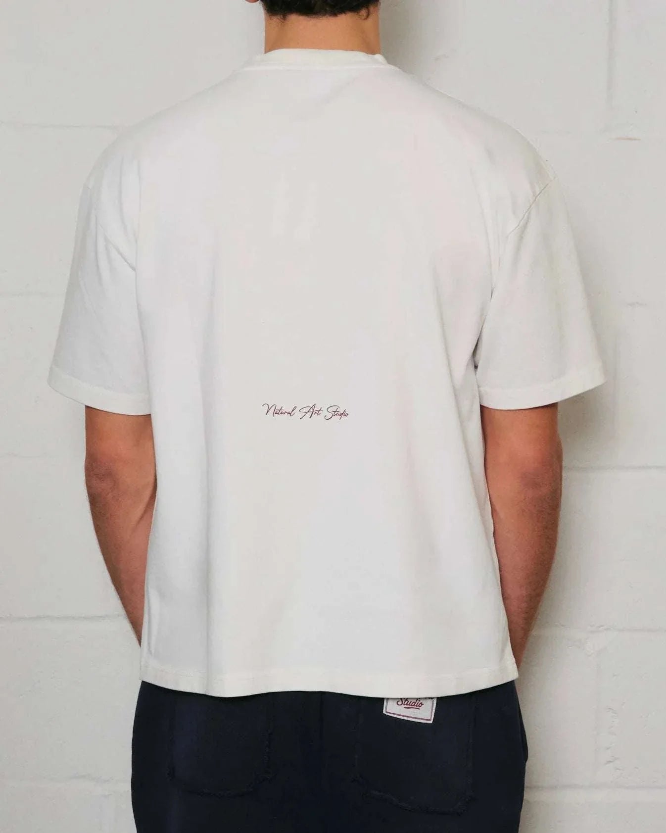 Back view of Natural Art Studio white cotton tee with red printed logo and boxy fit