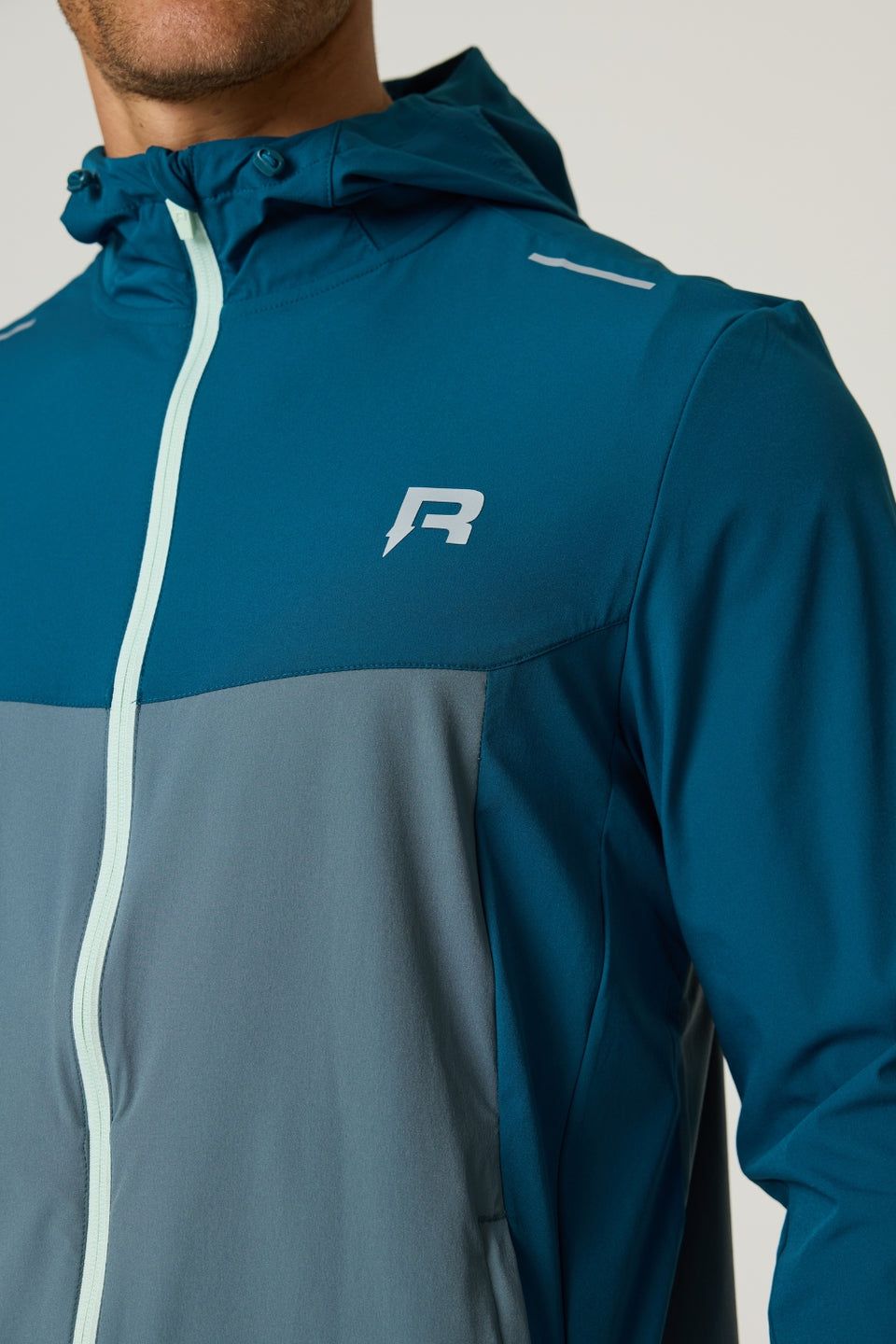 Reprimo Flight Windbreaker in tidal teal and blue steel with lightweight, wind-resistant polyamide fabric, zip pockets, and breathable back vent.