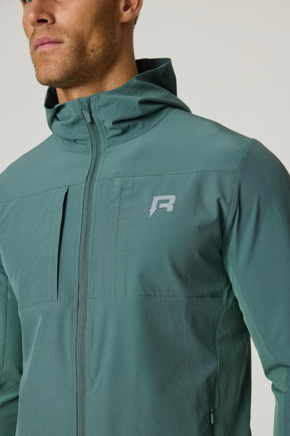 Man wearing botanical green Reprimo Glide Jacket with hood and front zipper