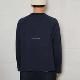 Back view of Natural Art Studio navy raglan long sleeve shirt with inside out raglan seams and screen print logo, worn by model