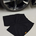 Black Studio By Charles Black studio shorts laid flat near a car wheel