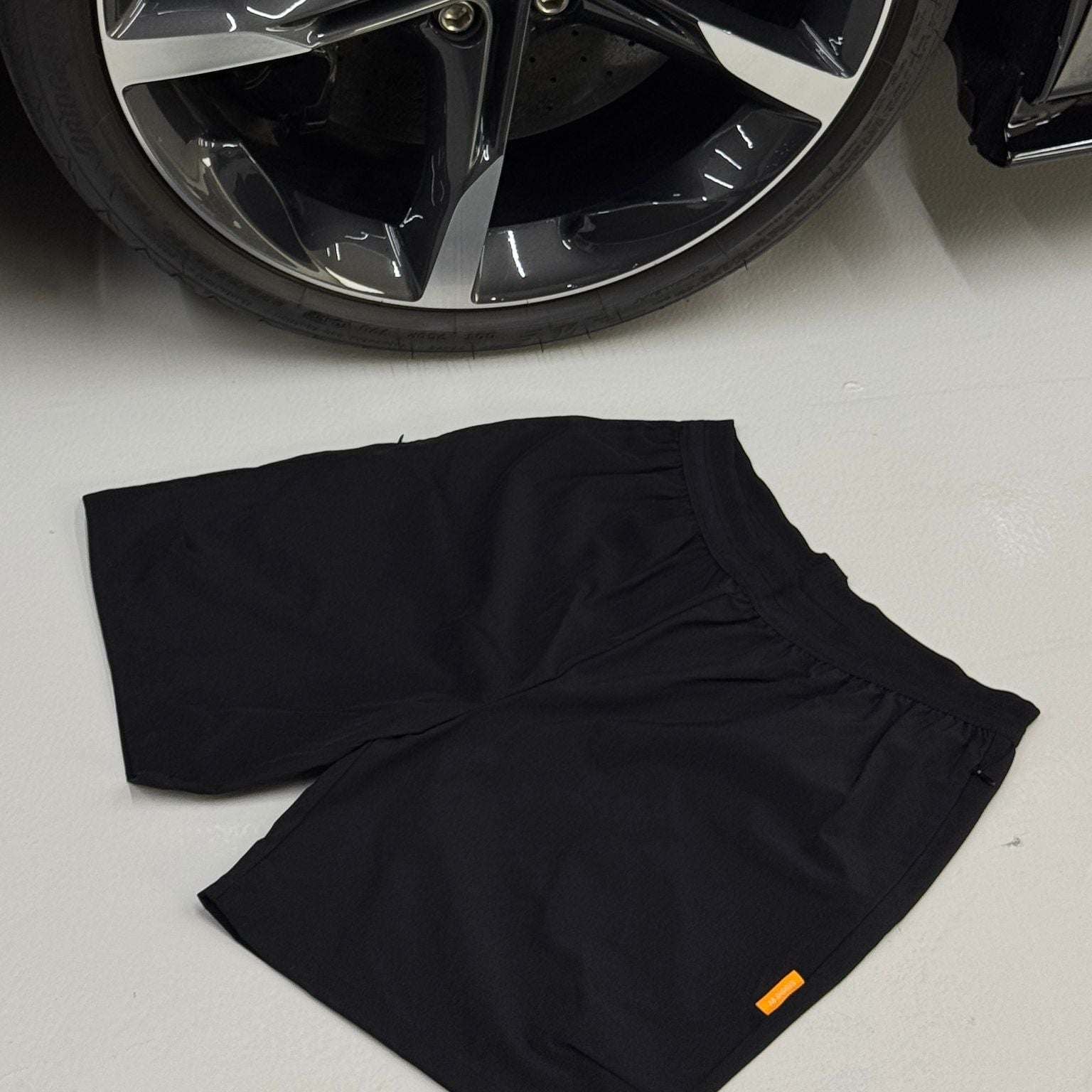 Black Studio By Charles Black studio shorts laid flat near a car wheel