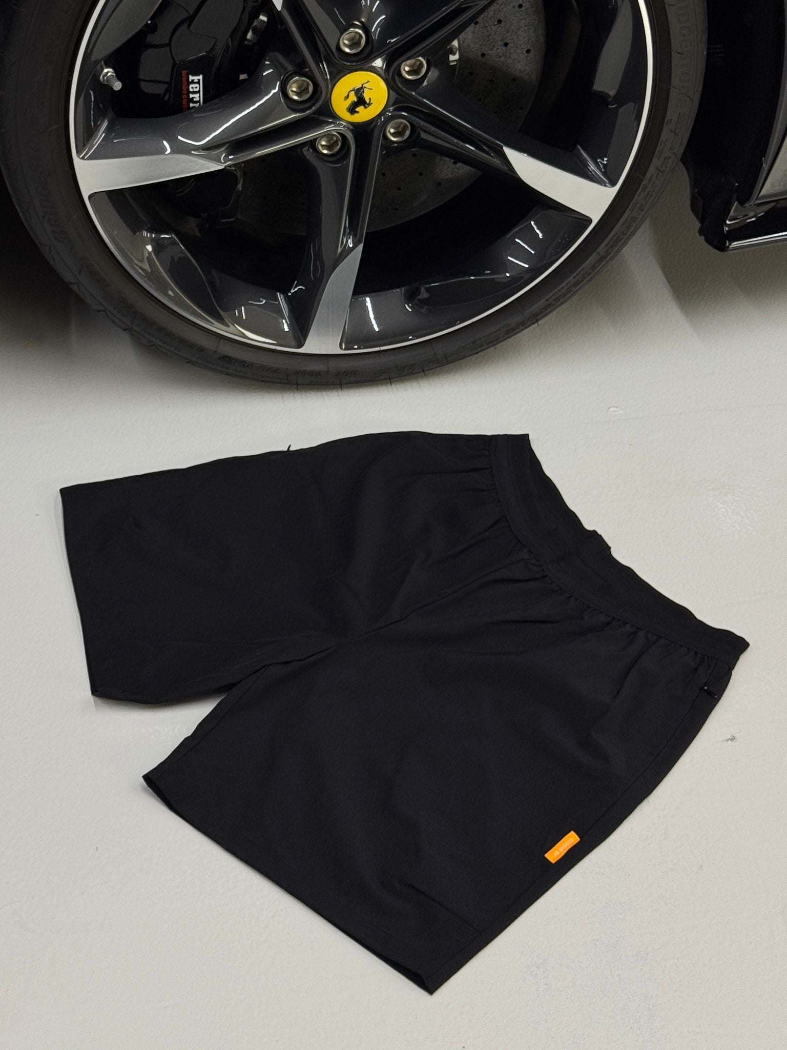 Black Studio By Charles Black studio shorts laid flat near a car wheel