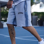Last Lesson Blue Sprayed Shorts on person walking in urban setting.