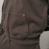 Close-up of brown Natural Art Studio NAS Appliqué Hoodie showing raw seams on cuffs and metal rivet on pocket detail