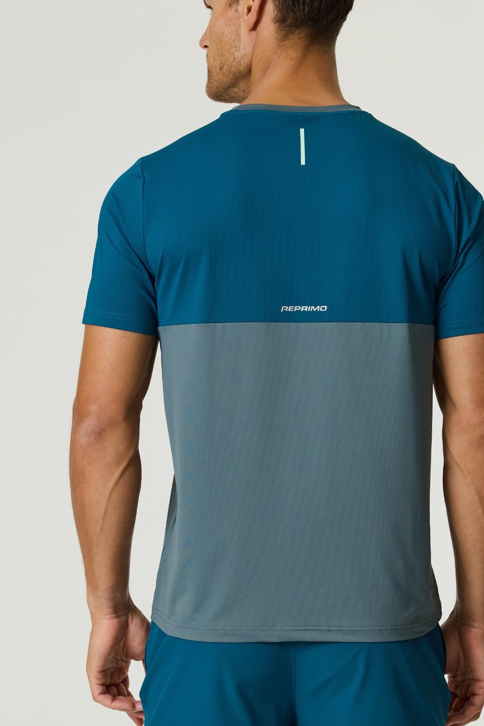 Back view of a man wearing a Reprimo Flight T-Shirt in tidal teal and blue steel with lightweight, breathable fabric and reflective strip for visibility.