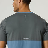 Back view of a man wearing a Reprimo Flight T-Shirt in Air Force Blue and Gunmetal with reflective strip and logo, showcasing athletic fit and lightweight breathable fabric